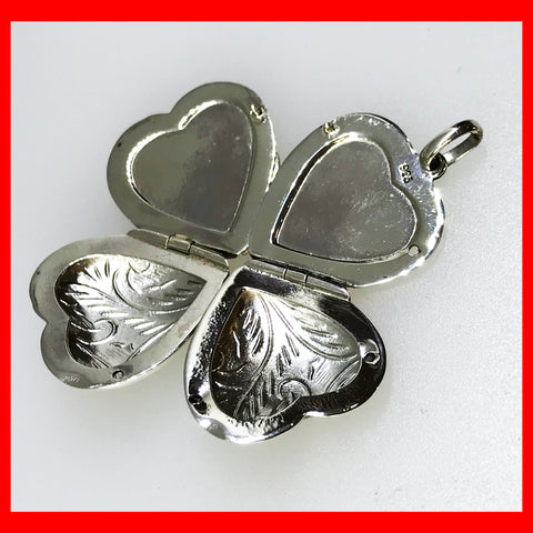 A sterling silver heart-shaped locket with clover shaped details on the sides, designed to hold four pictures.